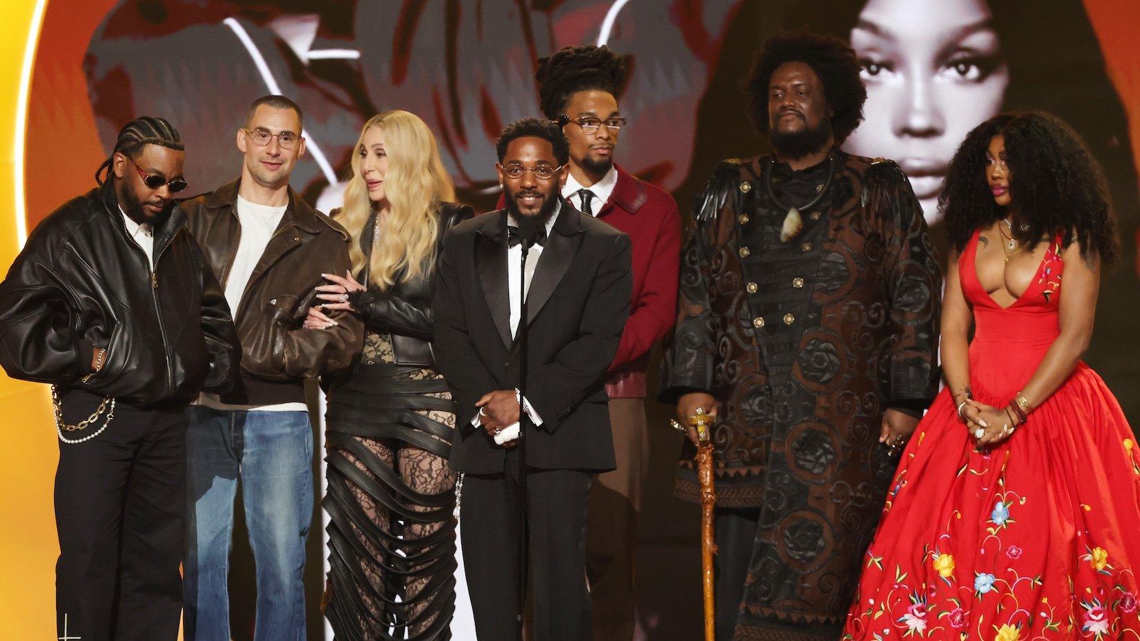 A photo of Kendrick Lamar and SZA winning the Grammy for Record Of The Year at the 2026 Grammys. In the photo are (L-R) Sounwave, Jack Antonoff, Cher, Kendrick Lamar, Scott Bridgeway, Kamasi Washington, and SZA.