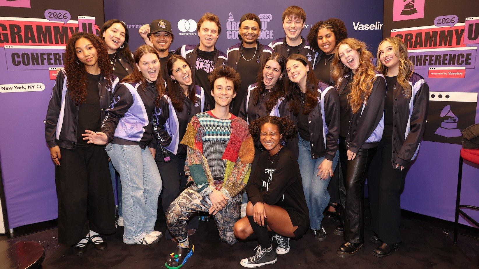 A photo of Jacob Collier (center) and WILLOW (center-right) posing with Grammy U members at the 2026 Grammy U Conference in New York City. They are smiling and looking to camera. The background features Grammy U Conference branding and graphics.